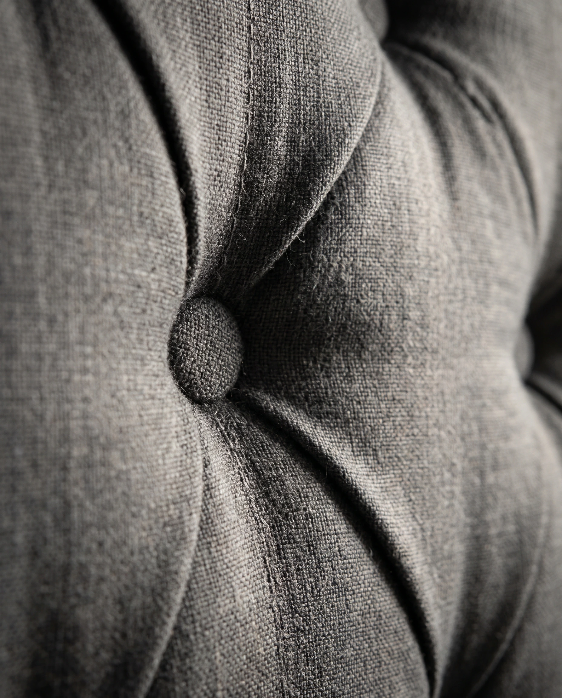 Close-up of deep button detailing and neat stitching on a slate grey upholstered headboard